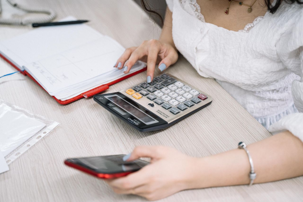 about-us-02 Close-up of a woman using a calculator and phone at her office desk.